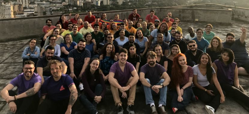 Foto de funcionários da Provu em terraço com camisetas coloridas formando um arco-íris humano