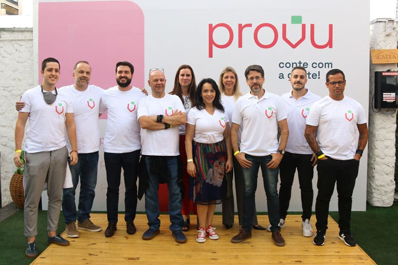 7 homens e 3 mulheres da Provu posando para foto, em frente a um painel com a marca da Provu e a frase "Conte com a gente"